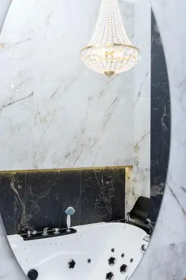 a mirror in a bathroom with a tub and a chandelier at Kazimierz Studio with Jacuzzi by Renters Prestige in Kraków