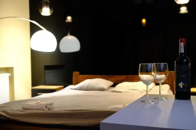 two wine glasses on a table next to a bed at City Apartment Getta in Kraków