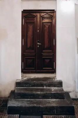 a wooden door in a white building with stairs at Native Apartments Dunajewskiego 2 in Kraków