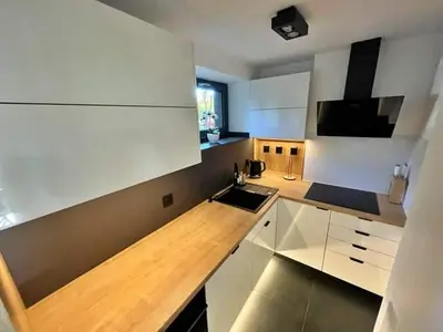 a kitchen with white cabinets and a wooden counter top at Dream House 8 osób - cały dla Ciebie in Gdów