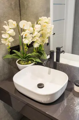 a white sink on a bathroom counter with flowers at Family Center Apartments in Kraków
