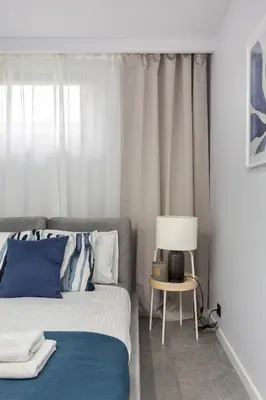 a bedroom with a bed and a table with a lamp at Family Center Apartments in Kraków
