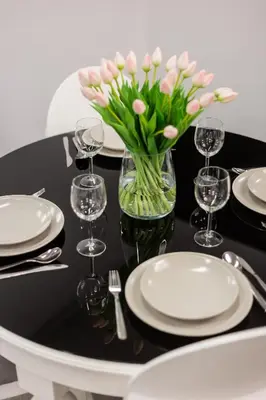 a table with plates and a vase of pink flowers at Family Center Apartments in Kraków