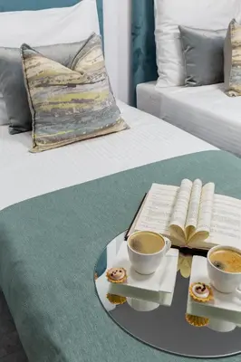 a table with two cups of coffee and a book on a bed at Family Center Apartments in Kraków