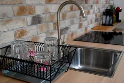a kitchen sink with glasses in a dish drying rack at Stay in the Heart of Kraków in Kraków