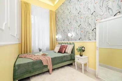a bedroom with a green bed with a bird wallpaper at Krakow Old Town Apartments in Kraków