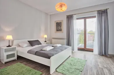 a white bedroom with a bed and a large window at Family Apartment by Tyzenhauz in Kraków