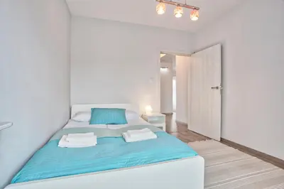 a white bedroom with a blue bed in a room at Family Apartment by Tyzenhauz in Kraków