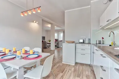 a kitchen and dining room with a white table and chairs at Family Apartment by Tyzenhauz in Kraków
