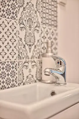 a bathroom sink with aaucet and a wall at Family Apartment by Tyzenhauz in Kraków