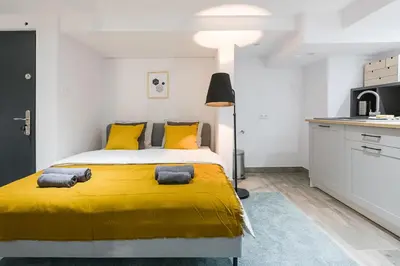 a bedroom with a yellow bed and a kitchen at Cosy Apartment in Perfect Location in Kraków