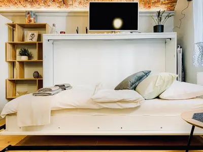 a white bed with pillows and a tv on top at Unique studio perfect for couples, Old Podgórze in Kraków