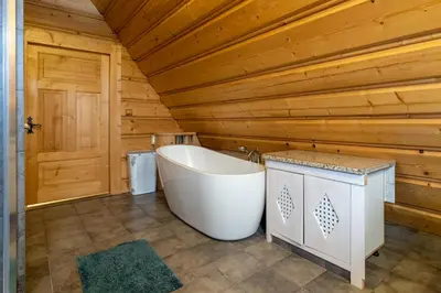 a bathroom with a tub and a wooden wall at Willa Sołdrówka in Kocierz Rychwałdzki