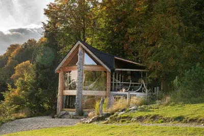 a small house with a black roof on a hill at Górna Chata Mountains Chalet - Stable Cottage in Ochotnica Górna