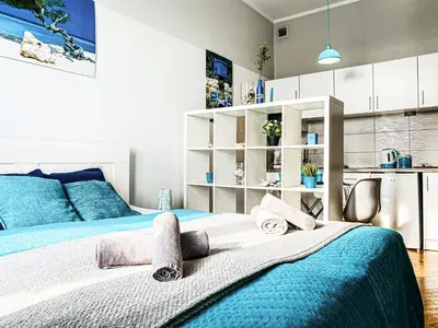 a bedroom with a blue and white bed and a kitchen at Apartment next to Wawel Castle, Vistula River & Old Town Cracow in Kraków