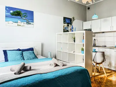 a bedroom with a large bed and a kitchen at Apartment next to Wawel Castle, Vistula River & Old Town Cracow in Kraków
