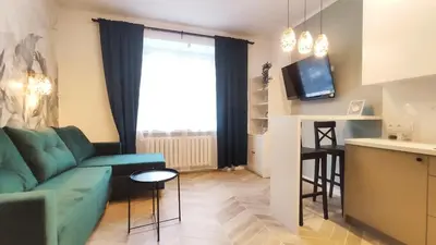 a living room with a blue couch and a kitchen at Daszyńskiego 18 by Homeprime in Kraków