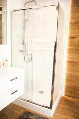 a glass shower in a bathroom with a sink at Mogilska Tauron Arena Two Bedroom Apartment in Kraków