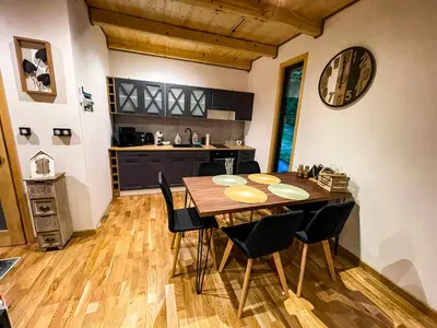 a kitchen and dining room with a wooden table and chairs at Leśne Zacisze Iwkowa in Iwkowa