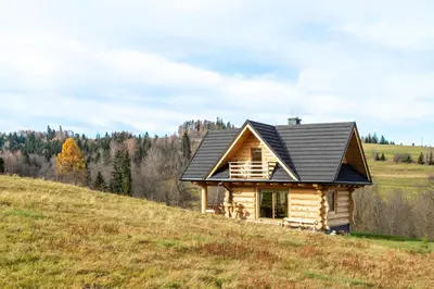 a log cabin on a hill with a black roof at Bacówka na Kubanówce in Rdzawka