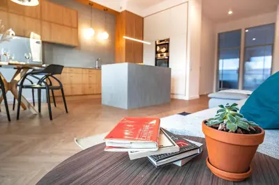 a living room with a table with books and a plant at Kossak 5 Suites in Kraków