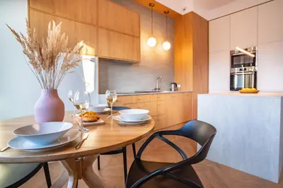 a kitchen with a wooden table with chairs and a vase at Kossak 5 Suites in Kraków