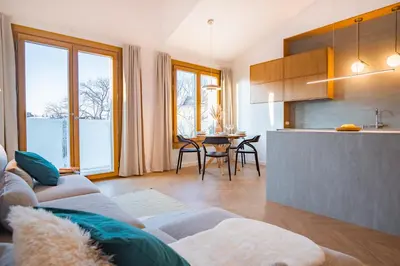 a living room with a couch and a kitchen at Kossak 5 Suites in Kraków