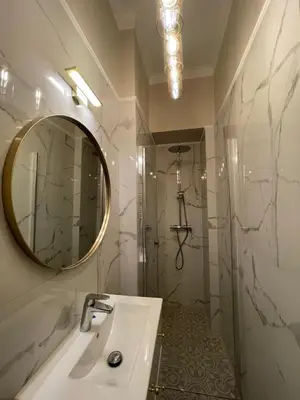 a bathroom with a sink and a mirror and a shower at Starowiślna Center Apartments in Kraków
