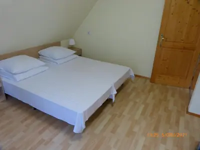 a bedroom with a white bed and a wooden floor at Willa Roztoczanka in Rabka
