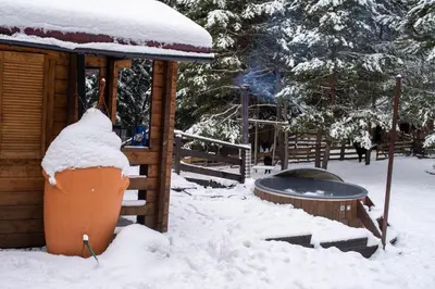 a log cabin with snow on the ground next to a grill at Beczki Pod Lasem in Trzemeśnia