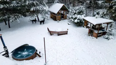 a snow covered yard with a hot tub and a cabin at Beczki Pod Lasem in Trzemeśnia