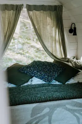 a bed in a camper with a window at Beczki Pod Lasem in Trzemeśnia