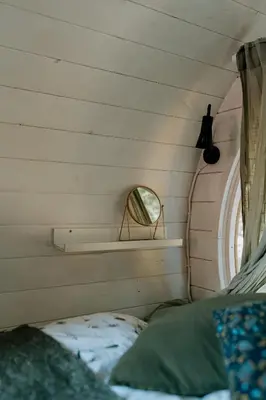 a small bedroom with a mirror and a bed at Beczki Pod Lasem in Trzemeśnia