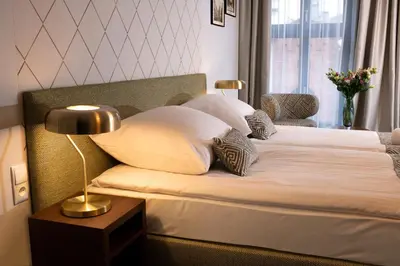 a bedroom with a bed with pillows and a lamp at Xerion Hotel in Kraków