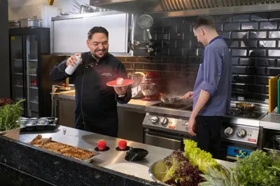two men standing in a kitchen preparing food at Xerion Hotel in Kraków