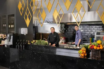 two men standing behind a counter in a kitchen at Xerion Hotel in Kraków