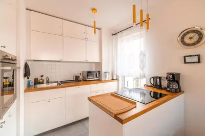 a kitchen with white cabinets and a wooden counter top at Apartament Chmielna Gold in Kraków