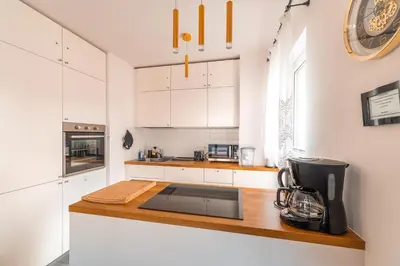 a kitchen with white cabinets and a counter top at Apartament Chmielna Gold in Kraków