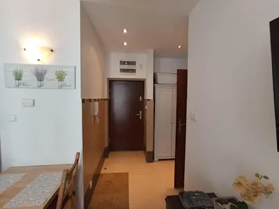 a room with a table and a kitchen with a door at Apartament Wielopole 17 in Kraków