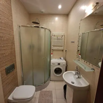 a bathroom with a toilet sink and a washing machine at Apartament Wielopole 17 in Kraków