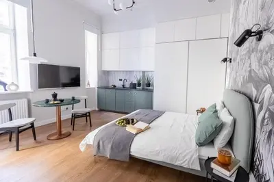 a bedroom with a bed and a table and a kitchen at LION apartments - Premium STUDIO with BALCONY in Kraków
