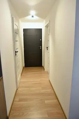 a hallway with a black door and a wooden floor at Dwa Widoki Apartamenty in Zubrzyca Górna