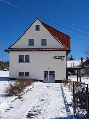 a white building with a red roof in the snow at Dwa Widoki Apartamenty in Zubrzyca Górna