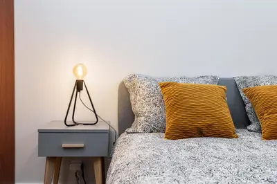 a bed with yellow pillows and a lamp on a night stand at St. Florian cozy loft in Kraków
