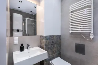 a bathroom with a sink and a toilet and a mirror at St. Florian cozy loft in Kraków