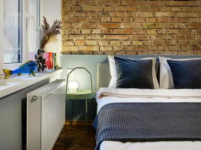 a bedroom with a bed and a brick wall at Silent blue apartment / Kochanowskigo St in Kraków