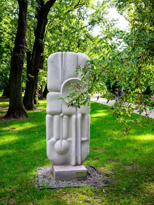 a stone chair sitting in the grass in a park at Silent blue apartment / Kochanowskigo St in Kraków