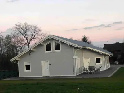 a small white house with a table and chairs at Babiogórska Perełka w skandynawskim stylu z sauną i kominkiem in Jordanów
