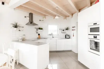 a white kitchen with white cabinets and a sink at Babiogórska Perełka w skandynawskim stylu z sauną i kominkiem in Jordanów