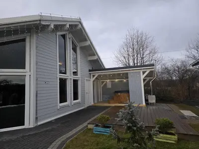 a white house with a porch and a deck at Babiogórska Perełka w skandynawskim stylu z sauną i kominkiem in Jordanów